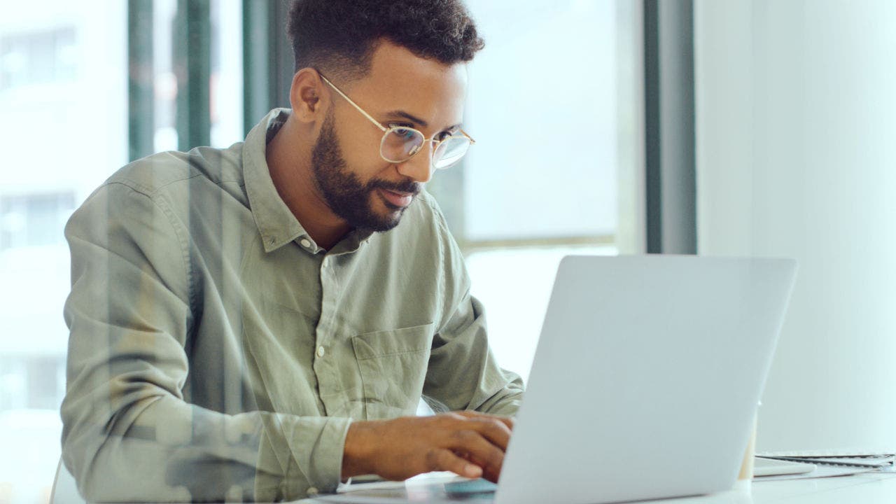 Shot of a young businessman using a laptop in a modern office.