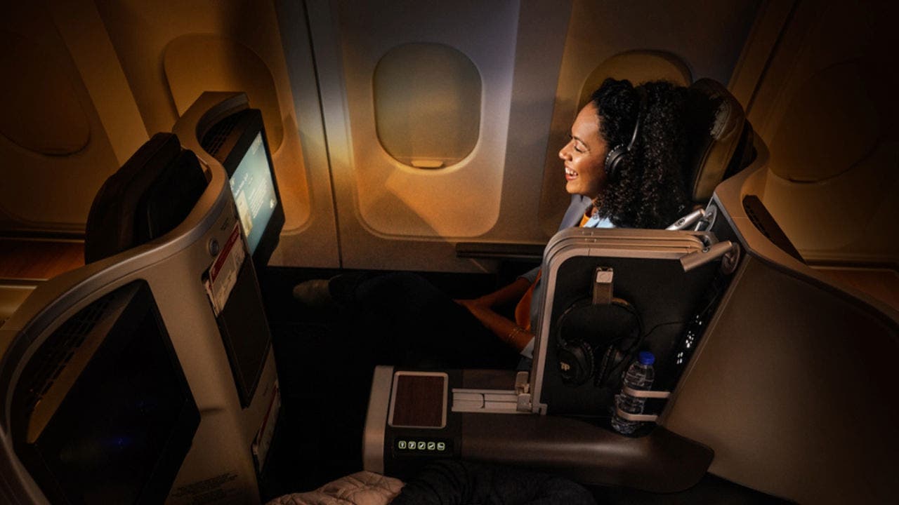 Smiling passenger, in Executive Class, sitting in a large, spacious and more comfortable chair, in a calm and dark environment, without people around it. You are watching some kind of entertainment on board, on the chair screen, with the TAP headphones put on.