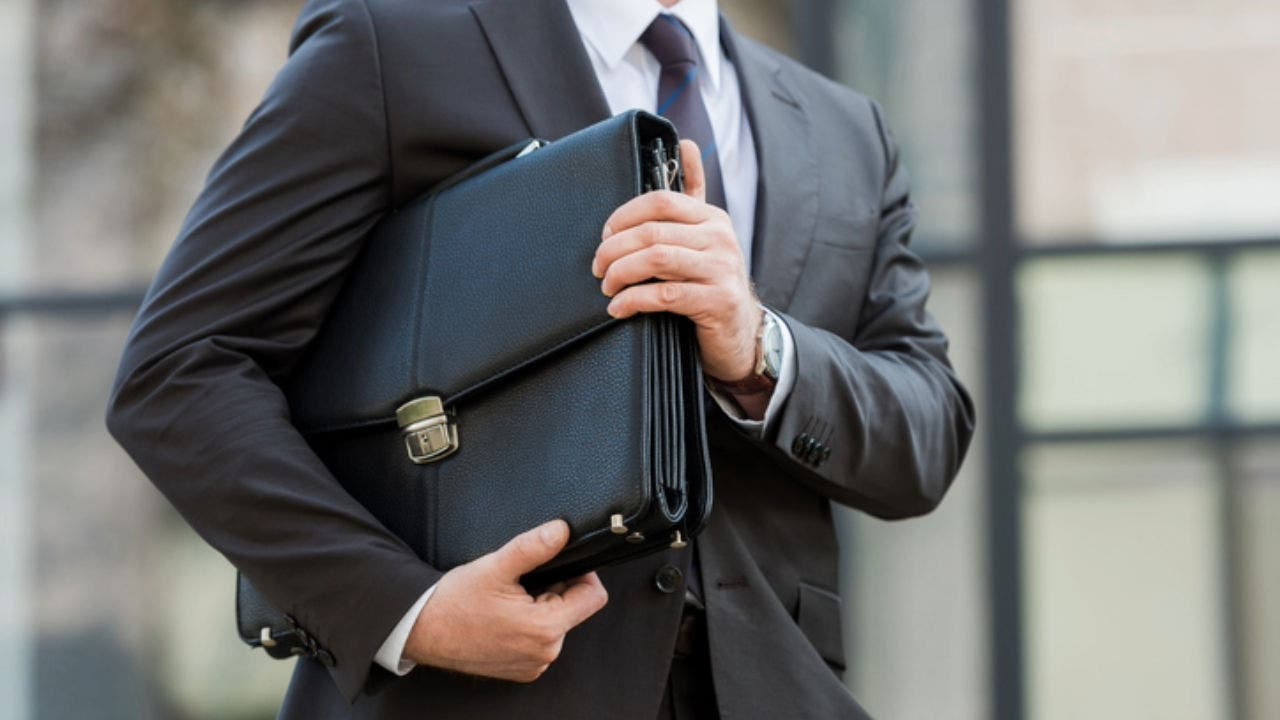 cropped view of man holding leather briefcase outside